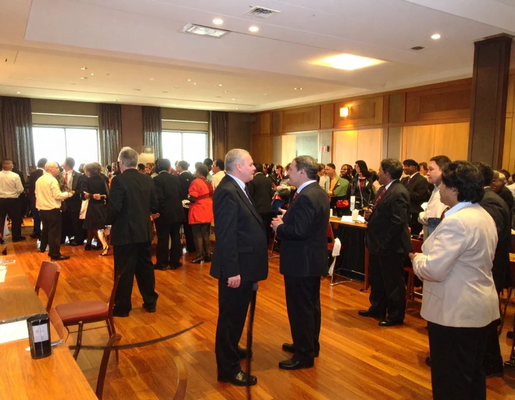 Attandees standing in groups in acorporate event, who are ll waiting for the mentalist to perform.